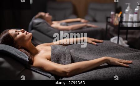 side view on young relaxed women lying on bed after face lift procedure, good-looking female takes care of their skin health Stock Photo