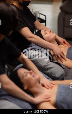 two caucasian middle-aged women enjoy beauty procedures, face lift massage, they want smoothy skin without wrinkles, anti aging massage on neck and sh Stock Photo