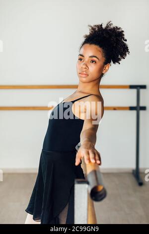 Young thoughtful woman looking away while leaning on barres at dance studio Stock Photo