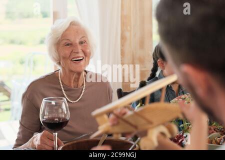 Senior woman smiling while she sitting at dinner table she happy for her son and his family Stock Photo