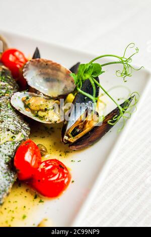 A close-up of mussels and cherry tomatos as a garnish on a white plate Stock Photo
