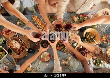 High angle view of group of people holding glasses and toasting with red wine at the table during dinner Stock Photo