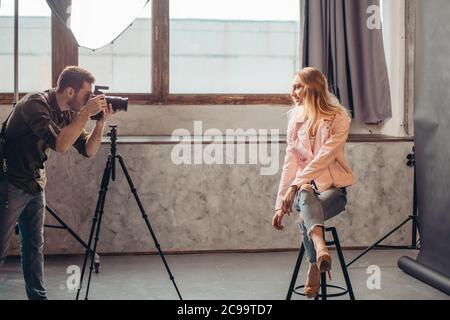 talented photographer working with a beautiful fair-haired model in fashion casual clothes, side view photo.hobby, interest Stock Photo