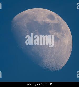 London, UK. 29 July 2020. A 72% illuminated Waxing Gibbous Moon above London in hazy blue sky, photographed through a telescope, shows crater details on the south pole. Credit: Malcolm Park/Alamy Live News Stock Photo