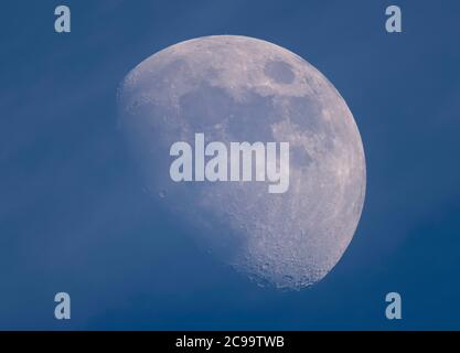 London, UK. 29 July 2020. A 72% illuminated Waxing Gibbous Moon above London in hazy blue sky, photographed through a telescope, shows crater details on the south pole. Credit: Malcolm Park/Alamy Live News Stock Photo