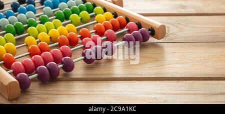 School abacus with colorful beads on wooden desk, close up view, copy space. Kids learning count, children math class concept Stock Photo