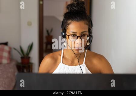 Working brazilian young woman in bedroom. Telemeeting. Video conference. Remote work. Call center home. Stock Photo