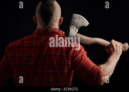 rear view of bearded mohawk man with axe on shoulder in studio Stock Photo