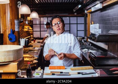 Japanese crazy chef with puzzled look in restaurant. Asian unexperienced man in the first working day. close up photo. chef doesn't know how to prepar Stock Photo