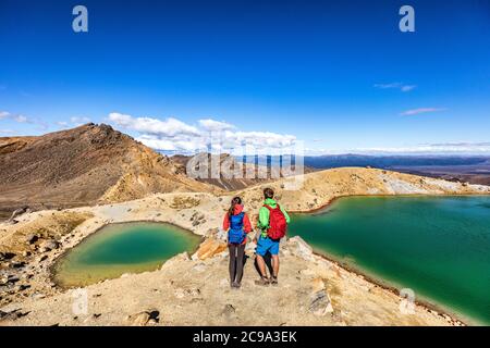New Zealand popular tourist hiking hike in Tongariro Alpine Crossing National Park. Tramping trampers couple hikers walking on famous destination in Stock Photo