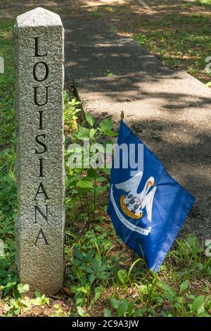 The name Louisiana engraved in a granite pillar with the flag of the state beside it in a park Stock Photo