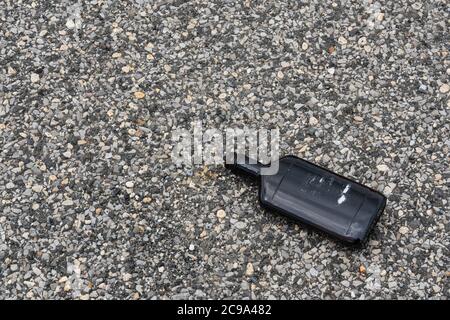 discarded empty dark brown whisky bottle with the label ripped off on a macadam sidewalk Stock Photo