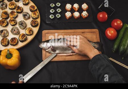 man using a knife to cut the backbone of the fish. close up top view shot. Stock Photo