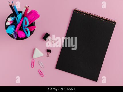 Black empty notebook blank, colorful stationery on pink background. Flat lay, copy space Stock Photo