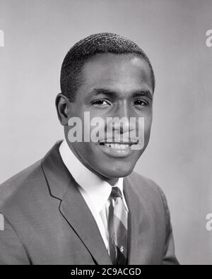 1960s PORTRAIT OF SMILING PROFESSIONAL AFRICAN-AMERICAN MAN WEARING SUIT AND TIE LOOKING AT CAMERA - n2009 HAR001 HARS BALANCE PLEASED JOY LIFESTYLE JOBS STUDIO SHOT HEALTHINESS MANAGER COPY SPACE CARING PROFESSION CONFIDENCE EXECUTIVES BANKER EXPRESSIONS B&W EYE CONTACT SUCCESS MUSTACHE SKILL SUIT AND TIE OCCUPATION SELLING HAPPINESS SKILLS WELLNESS HEAD AND SHOULDERS CHEERFUL STRENGTH MUSTACHES AFRICAN-AMERICANS COURAGE AFRICAN-AMERICAN AND CAREERS KNOWLEDGE LEADERSHIP PROGRESS BLACK ETHNICITY PRIDE OF OPPORTUNITY FACIAL HAIR OCCUPATIONS SMILES BOSSES CONCEPTUAL JOYFUL STYLISH ATTORNEY Stock Photo