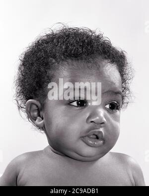 1940s 1950s PORTRAIT CHARMING CUTE WIDE-EYED AFRICAN-AMERICAN BABY GIRL SITTING UPRIGHT LOOKING TO SIDE - n599 HAR001 HARS JUVENILES ATTENTIVE BABY GIRL BLACK AND WHITE HAR001 OLD FASHIONED AFRICAN AMERICANS Stock Photo
