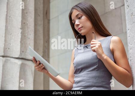 Tablet business woman worker serious working at office or courthouse reading news email. Asian Businesswoman lawyer using pc computer with reading Stock Photo