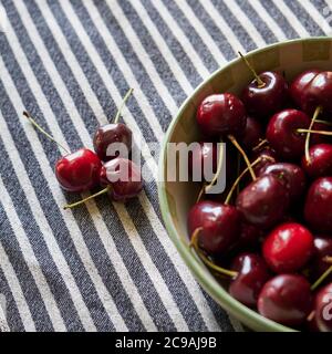 Fresh dark red cherries in a bowl. The fresh fruit are long stem cherries. Stock Photo