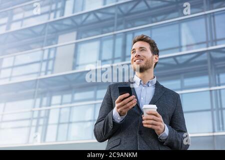Business man holding phone drinking coffee at bank office thinking of the future. Aspirational businessman dreaming of career hope Stock Photo