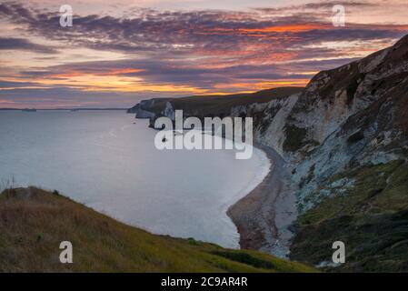 Dungy Head, West Lulworth, Dorset, UK.  29th July 2020.  UK Weather.  The clouds are tinged with and orange glow at sunset viewed from Dungy Head at West Lulworth in Dorset looking west towards Man O'War Bay and Durdle Door.  Picture Credit: Graham Hunt/Alamy Live News Stock Photo