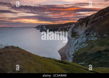 Dungy Head, West Lulworth, Dorset, UK.  29th July 2020.  UK Weather.  The clouds are tinged with and orange glow at sunset viewed from Dungy Head at West Lulworth in Dorset looking west towards Man O'War Bay and Durdle Door.  Picture Credit: Graham Hunt/Alamy Live News Stock Photo