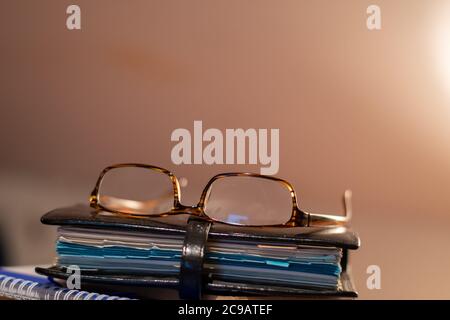Pair of reading glasses resting on top of a leather-bound personal organiser Pair of reading glasses resting on top of a leather-bound personal organiser