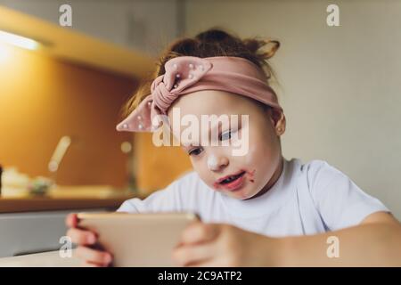 Girl eating at the table playing on the phone.