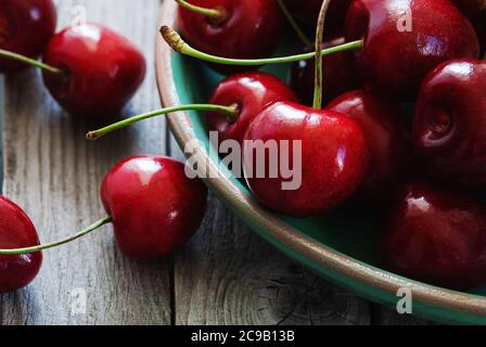 cherries in a bowl on wooden table closeup Stock Photo