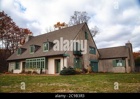 Two-story house in European style with green doors and windows, bay window and three dormer windows in front, little balcony and french doors on right Stock Photo