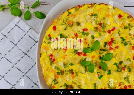 Omelette with vegetable and herbs. Top view on white background. Stock Photo