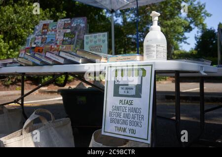 Signs at Lake Oswego's outdoor library remind readers to sanitize hands before and after browsing books to prevent the spread of the coronavirus. Stock Photo