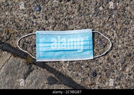 Close up of a disposable face mask on a street / pavement. Once protection, now polluting the environment. Stock Photo