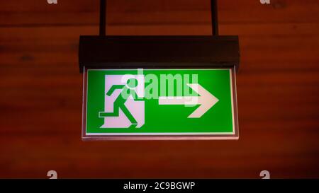 Panorama with an illuminated emergency exit sign. Neutral, brown background. Stock Photo