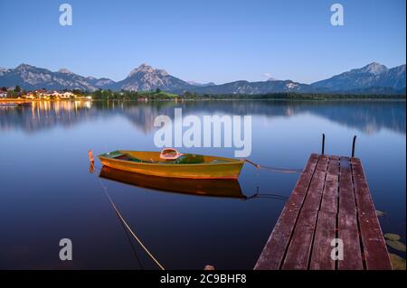 Hopfensee with rowing boat and wooden jetty, in the background the Tannheim Mountains, Allgäu, Bavaria, Germany Stock Photo