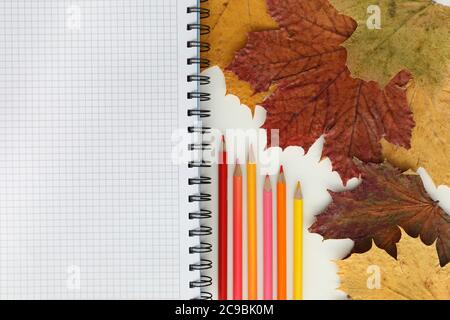 On the table are colored pencils and a notebook Stock Photo