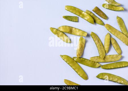 Frozen vegetables such as pea pods on a blue background. Copy space. Top view. Horizontal orientation Stock Photo