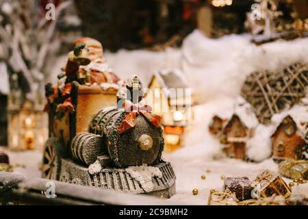 Christmas figurine of a train with a red bow on a showcase with artificial snow. Stock Photo