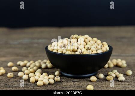 Raw soybeans in wooden bowl on wooden table background. Stock Photo