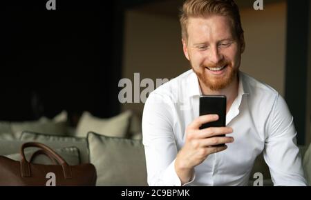 Happy young man using his smart phone at office Stock Photo