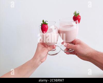 Couple's hands holding up glasses with strawberry buttermilk cocktail. Cheers. Stock Photo