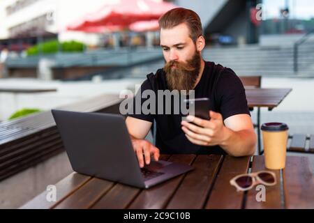 Man's hand using smart phone in modern interior street cafe, busy business man using cell phone and online technologies Stock Photo