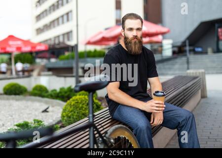 Young bearded man near his bicycle outdoors
