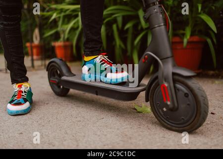 Closeup of the legs of a young urban man riding e scooter on the street Stock Photo