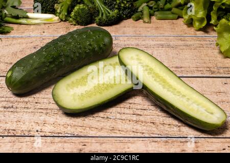 Green healthy cucumbers on a brown wooden background. Products for the keto diet, gluten-free diet and proper nutrition for weight loss. Stock Photo