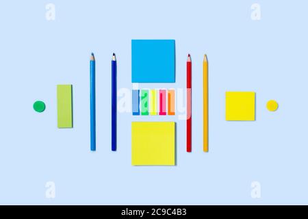 Back to school flat lay with colored pencils, paper clips, and stickers on blue background. Stock Photo