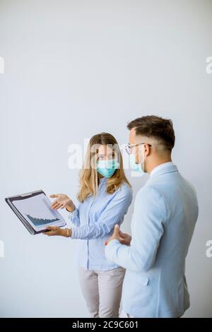 Business partners standing and looking at business results in the office while wearing face masks sa an virus protection Stock Photo