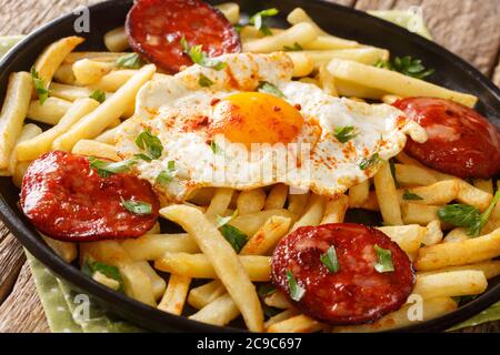 Huevos Rotos Recipe: Spanish Broken Eggs with potato and chorizo sausage close-up in a plate on the table. Horizontal Stock Photo