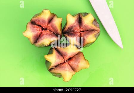 Top down image of three ripe green figs cut open with knife on green background Stock Photo