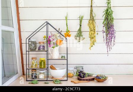 Collection of various herbal medicinal plants dry in glass jars and drying on wall. Modern shelf with jars mortar and pestle and bouquet of herbs. Stock Photo