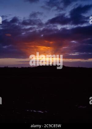 View WSW of Breedon on the Hill church, The Bulwarks Iron Age hillfort & Breedon Quarry, Leicestershire, England, UK: upward rays of a winter sunset. Stock Photo